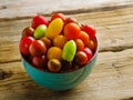 On a wooden table there is a bowl with multi-colored tomatoes. Minimalism. Vitamins, antioxidants. Healthy organic food ready to