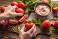 Ingredients for making tomato basil sauce, a bowl with fresh sauce and hands holding a ripe homemade tomatoes Royalty Free Stock Photo