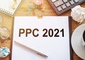 On a wooden table there is an office sheet of paper with the text PPC Pay Per Click. Business workspace with calculator, glasses Royalty Free Stock Photo