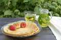 On a wooden table there is a plate with pancakes on which there are several strawberries, next to a transparent pitcher Royalty Free Stock Photo