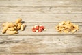 On a wooden table are three small piles of peeled peanuts, shells, whole peanuts. View from the side