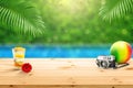 Wooden table top with with accessories glass of fruit juice camera and beach ball isolate with blured swimming pool background Royalty Free Stock Photo