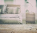 Wooden table top with blur of modern bedding with reading lamp Royalty Free Stock Photo