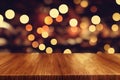 a wooden table top with blurry lights in the background of a room with a wooden floor and a wall Royalty Free Stock Photo