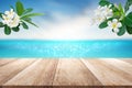 Wooden table top with blurry sea sun sky scenery decorate with plumeria flower branch tropical summer background Royalty Free Stock Photo