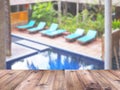 Wooden table top over blurry swimmimg pool background Royalty Free Stock Photo