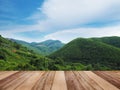 Wooden table top over green mountain range over blue sky background Royalty Free Stock Photo