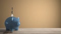 Wooden table top or shelf with blue piggy bank with coins, saving money for future investments, concept idea with orange colored Royalty Free Stock Photo