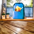 Wooden table top space for your products and a schoolbag in the kitchen background. Some school accessories on windowsill. Royalty Free Stock Photo