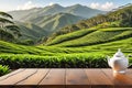 Wooden table top surface in foreground, sharpness out of focus: tea plantation undulating, mountain backdrop