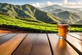 Wooden table top surface in foreground, sharpness out of focus: tea plantation undulating, mountain backdrop