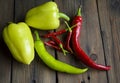 On a wooden table are two bell peppers, a hot green pepper, a hot red pepper and a lot of small chilies. Different types of pepper Royalty Free Stock Photo