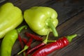 On a wooden table are two bell peppers, a hot green pepper, a hot red pepper and a lot of small chilies. Different types of pepper Royalty Free Stock Photo