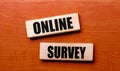 On a wooden table are two wooden blocks with the text question ONLINE SURVEY