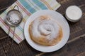 On a wooden table a vertuta sprinkled with powdered sugar and a towel, next to it is a bowl with white sauce Royalty Free Stock Photo