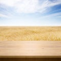 Wooden table with wheat field background. Blue sky over ripe yellow wheat field. Summer background, mock up for design Royalty Free Stock Photo