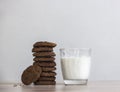 On a wooden table on a white background stands a stack of oatmeal cookies sunflower seeds a glass of milk