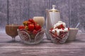 Two crystal vases with ripe strawberries, two glasses with cocktail, cup of coffee and white teapot stand on wooden table. Royalty Free Stock Photo