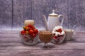 Two vases with strawberries, two glasses with cocktail, up of coffee, teapot stand on wooden table. Royalty Free Stock Photo