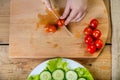 On a wooden table, a woman knives a regimen of tomatoes