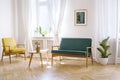 Wooden table between yellow armchair and green bench in white fl