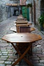 Wooden tables and chairs in cobbled alley with a vintage look.