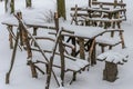 Wooden tables and chairs - furniture for a picnic handmade, stand among snow-covered woods strewn with snow Royalty Free Stock Photo