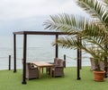 Wooden tables and wicker chairs under a canopy overlooking sea. Royalty Free Stock Photo