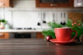 Wooden tabletop with red cup of coffee and blurred Christmas kitchen Royalty Free Stock Photo