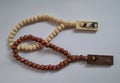 Wooden tasbeh a tool for calculating wirid, moslem prayer. Brown and cream tasbeh beads on white background.