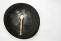 Wooden tea spoon full of sea salt on a black plate