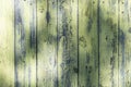 Wooden textural background with remnants of green paint from parallel vertical boards.