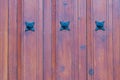 Wooden texture background. Closeup of a detail from a wooden red brown entrance door with three metal stars on the wooden planks. Royalty Free Stock Photo