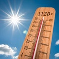 Wooden thermometer against clear blue sky, sun shining, marking warm 120?Ã¸F, sunny day
