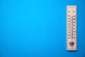 Wooden thermometer on blue background