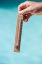 Wooden thermometer in hand in border swimming pool