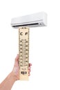 Wooden thermometer in hand in the front of air conditioner. Isolated on white background with copy space Royalty Free Stock Photo