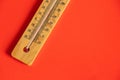 Wooden thermometer lies on a red background closeup