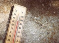 Wooden thermometer with red measuring liquid showing high temperature over 32 degrees Celsius on sunny day on old stone background