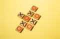 Wooden tic-tac-toe pieces arranged on a yellow background Royalty Free Stock Photo