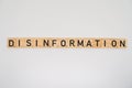 Wooden tile spelling the word disinformation isolated on a white background Royalty Free Stock Photo
