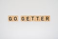 Wooden tile spelling the words go getter on a white background