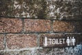 A wooden toilet sign on the old brick wall. Royalty Free Stock Photo