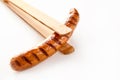 Wooden tongs holding a cooked, seared sausage Royalty Free Stock Photo