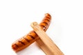 Wooden tongs holding a seared, barbecued sausage Royalty Free Stock Photo