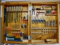 Wooden tool cabinet filled with technician equipment in home workshop.