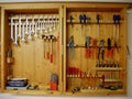 Wooden tool cabinet filled with technician equipment in home workshop.