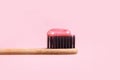 Wooden toothbrush with pink paste close-up on a pink background Royalty Free Stock Photo