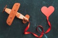 Wooden toy airplane biplane on a dark background with a red ribbon and a heart