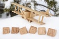 A wooden toy airplane in the snow, against the background of a forest and the word Russia made up of cubes. The concept Royalty Free Stock Photo